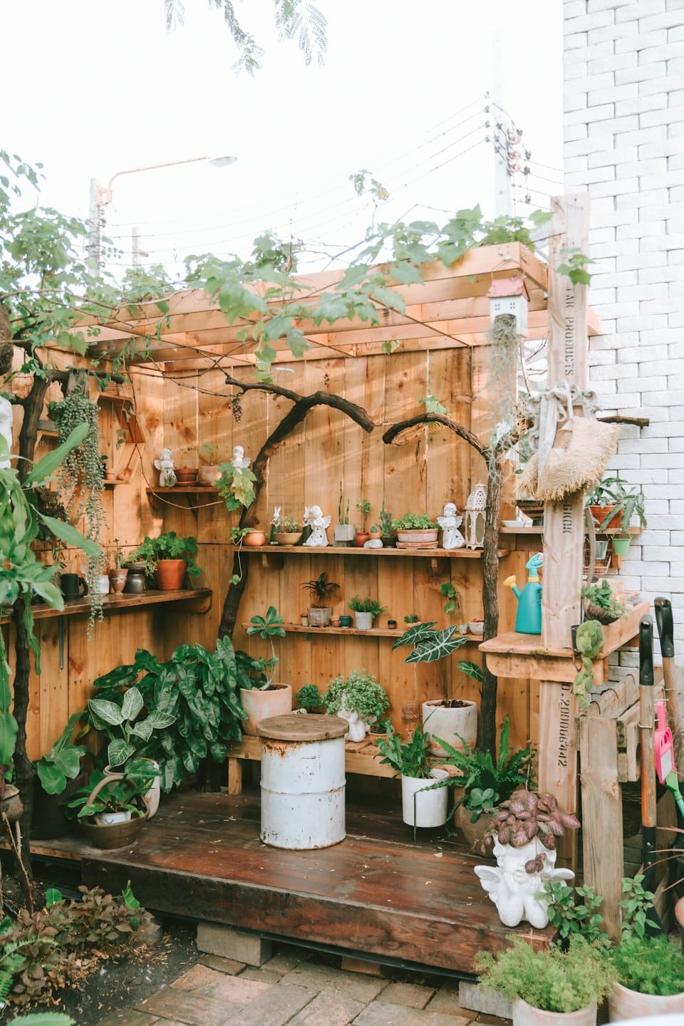 Potted plants and garden statues sit on wooden shelves.